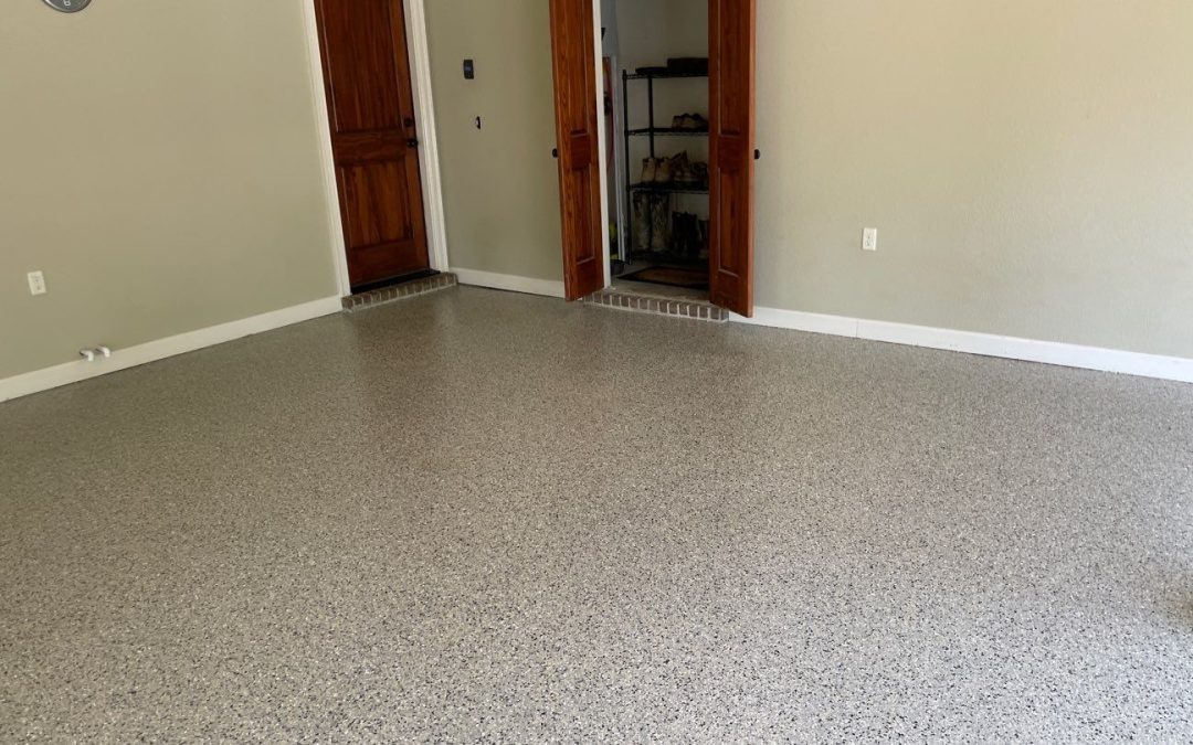 Garage interior featuring a polished concrete floor with a decorative finish, two wooden doors leading to an entryway, and a glimpse of storage space, highlighting Southern Floor Coating's concrete coating services in Little Rock.
