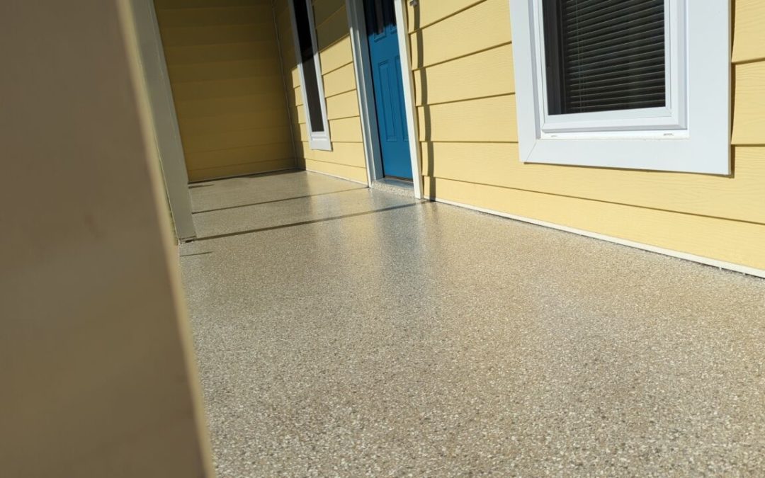 Front porch featuring polished concrete coating by Southern Floor Coating, with a yellow exterior wall and a blue door, showcasing durability and aesthetic appeal.