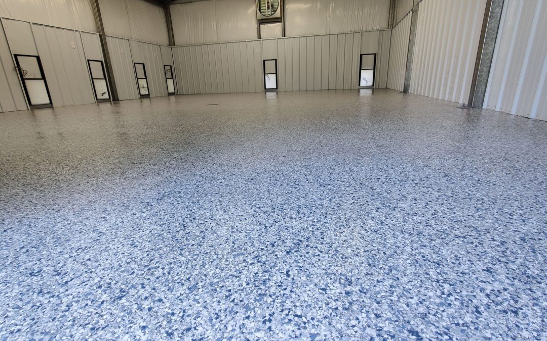 Commercial concrete floor with a blue and gray speckled coating, showcasing durability and aesthetics in a spacious interior setting.